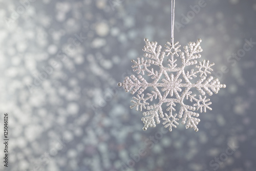 Silver diamond sparkling snowflakes on a silver background bokeh.