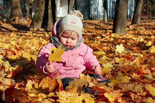 baby plays with Autumn leaves in the park