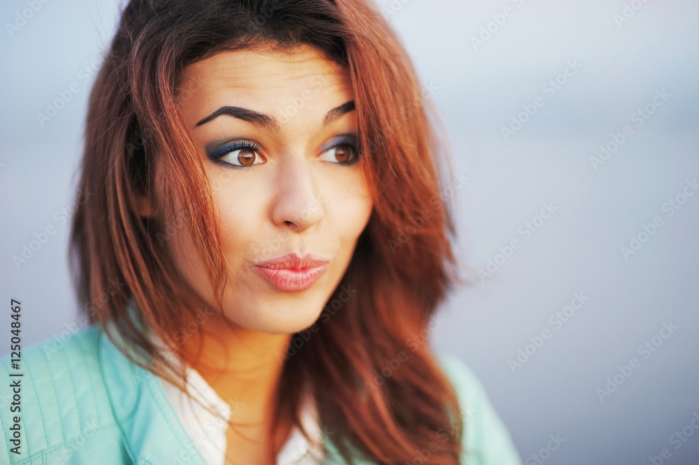 Portrait of cheerful beautiful brown-haired girl with a surprised look and a smile, close up. Portrait of cheerful beautiful brown-haired girl with a surprised look and a smile, close up.