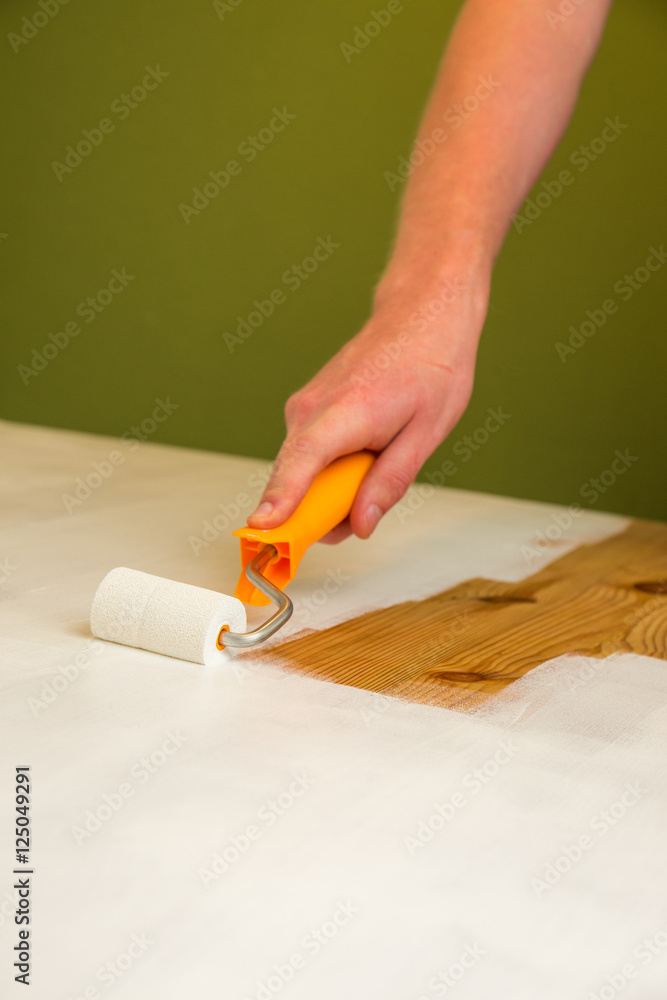 Ein Holztisch wird mit weißer Farbe lackiert Ein Holztisch wird mit weißer Farbe lackiert
