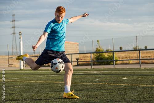 Soccer player kicking a ball at football pitch