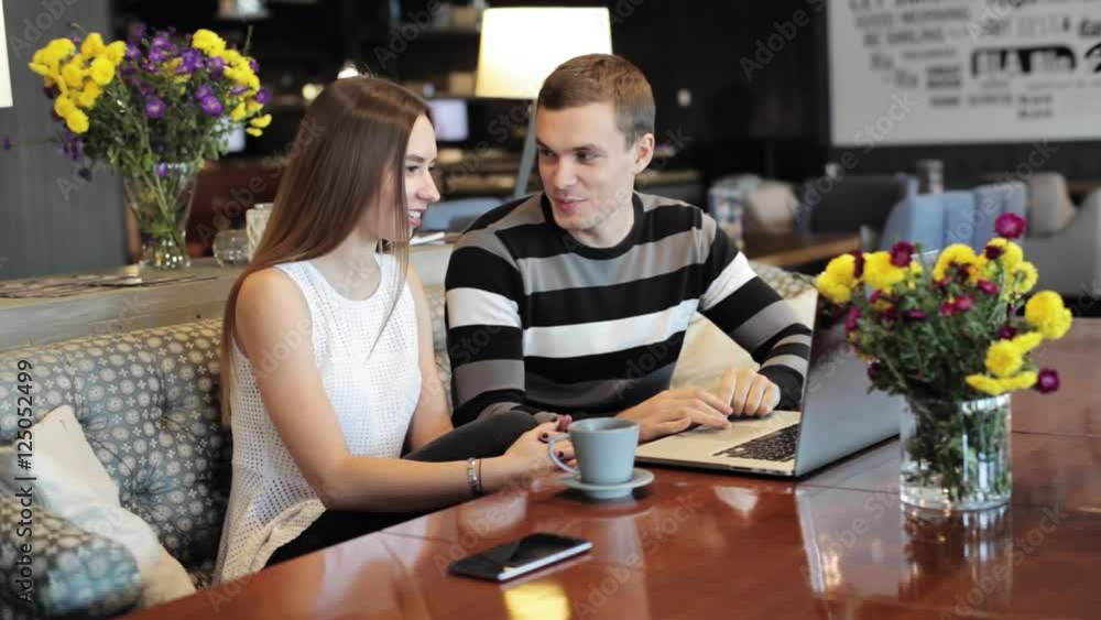 Young caucasian couple with modern laptop in cafe Young caucasian couple with modern laptop in cafe