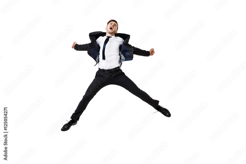 Young successful businessman in suit rejoicing, jumping over white background.