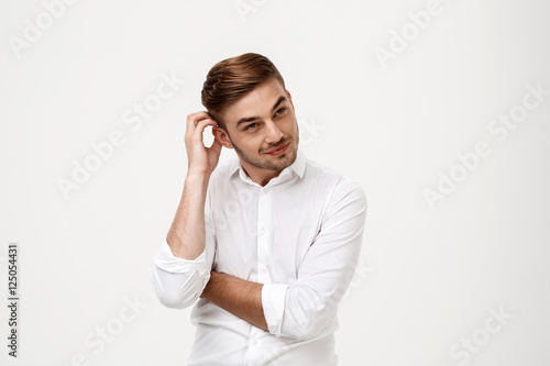 Young successful businessman thinking, posing over white background.