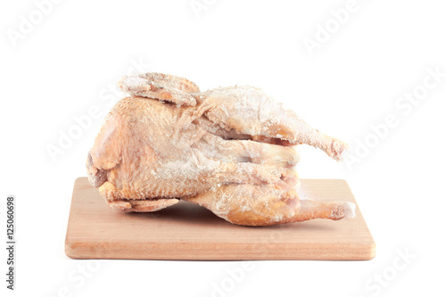 Frozen chicken carcass on a wooden chopping board
