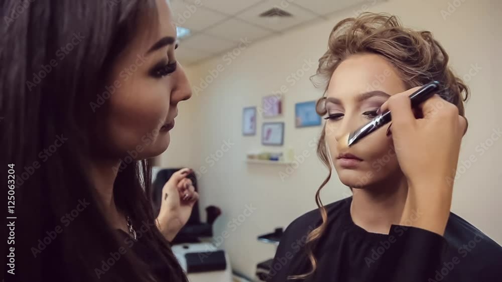 Make up artist doing professional makeup of young woman in beauty studio Make up artist doing professional makeup of young woman in beauty studio