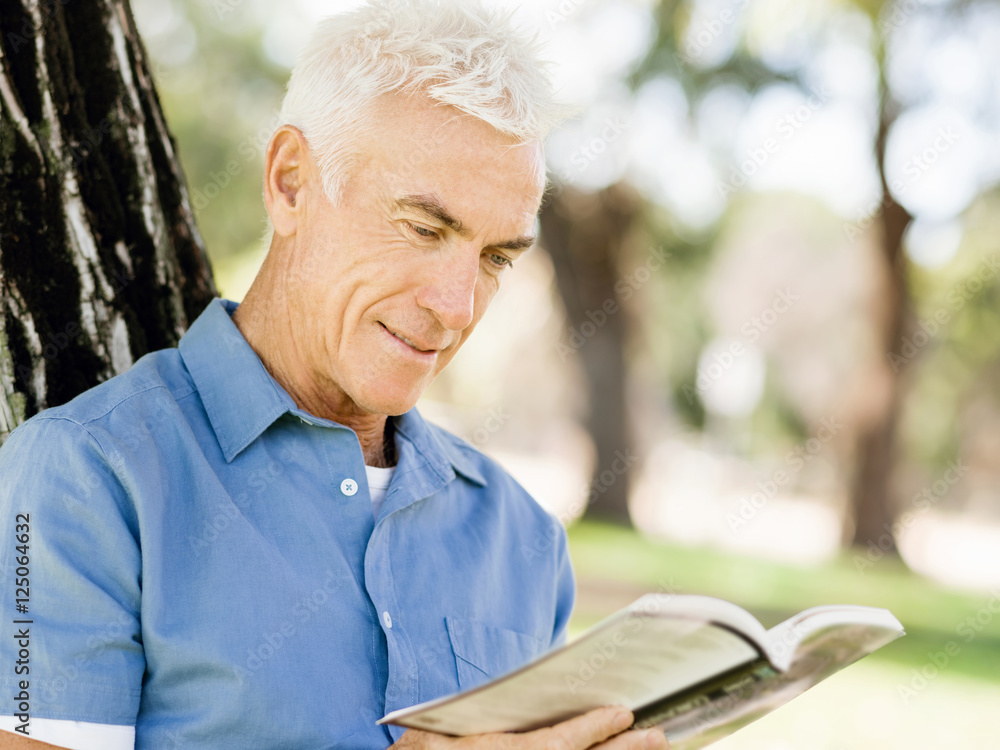 Senior man sittingin park while reading book Senior man sittingin park while reading book