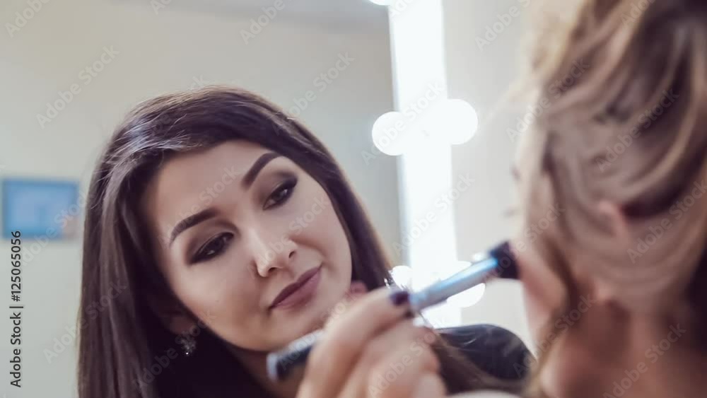 Make up artist doing professional makeup of young woman in beauty studio Make up artist doing professional makeup of young woman in beauty studio