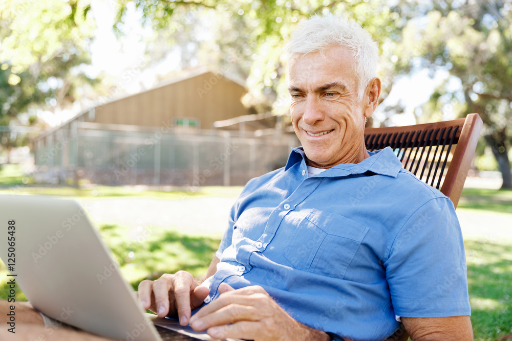 Senior man with notebook sitting in the park Senior man with notebook sitting in the park