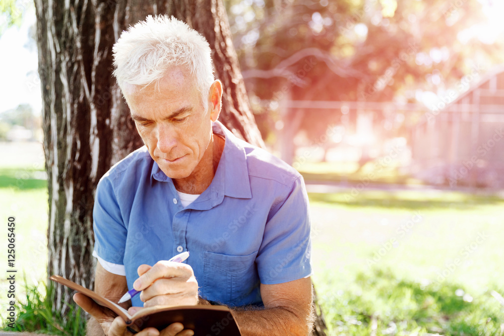 Senior man sittingin park while reading book Senior man sittingin park while reading book