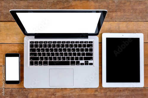 Office wooden table with blank screen laptop computer, blank screen smartphone and blank screen tablet.Top view .