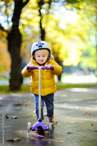 Toddler boy in helmet to ride scooter