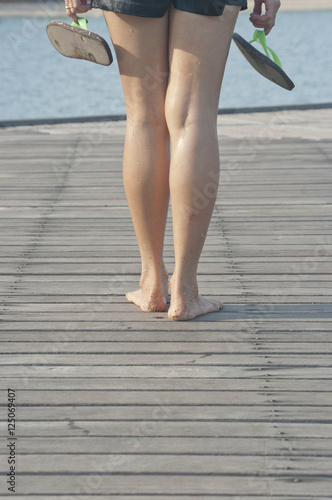 woman foot on the wood bridge on the beach