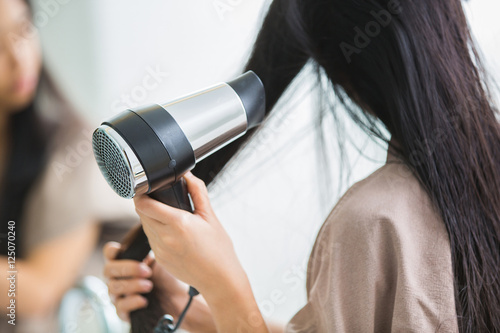 Woman with a hair dryer to heat the hair. photo