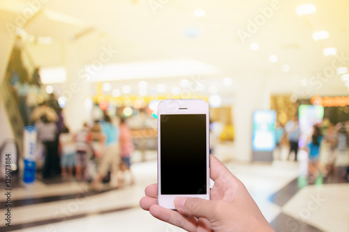 Man hand holding smartphone black screen with blur shopping zone background