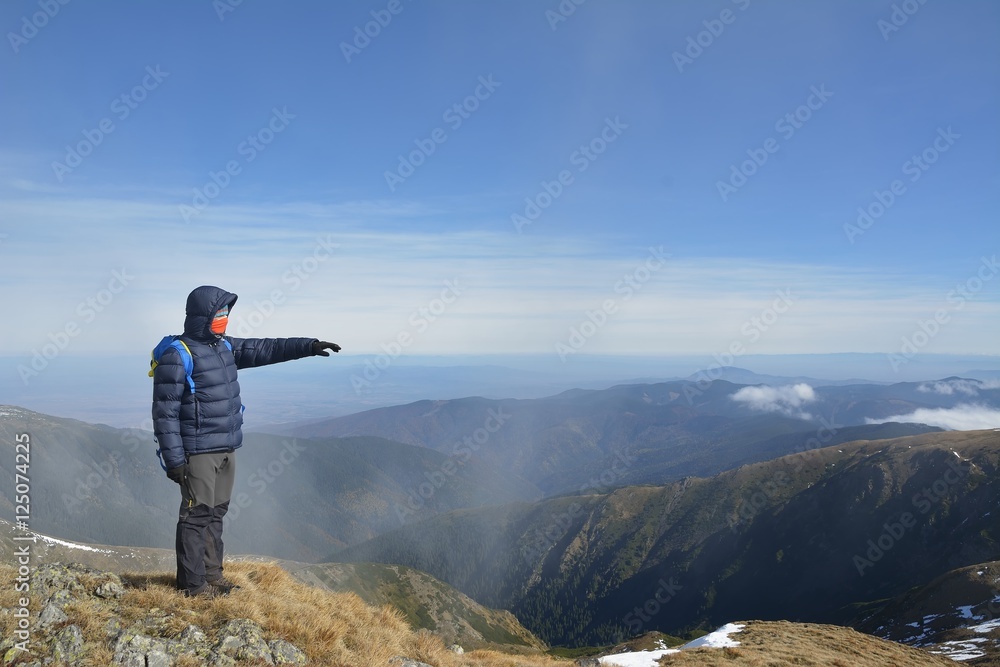 tourist man standing on a rock and hand pointing direction in mountains