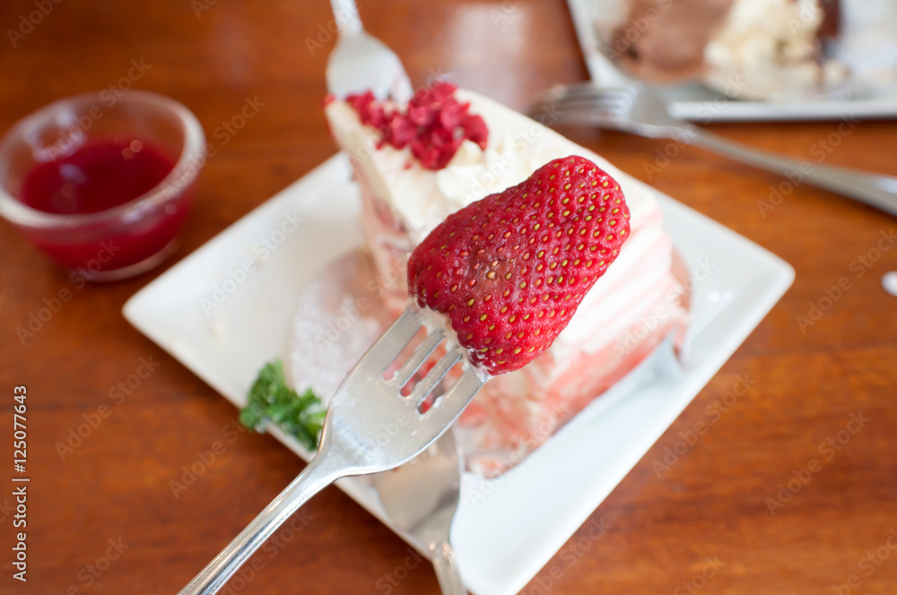 Strawberry on a fork,Crepe cake with strawberry sauce on table.selective focus Strawberry on a fork,Crepe cake with strawberry sauce on table.selective focus