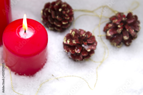 lit candles Christmas decoration with pinecones on snow