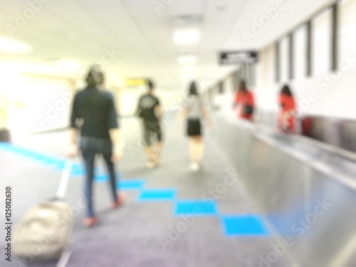 Traveler walking the airport terminal hall and a handbag behind her. Blured background.