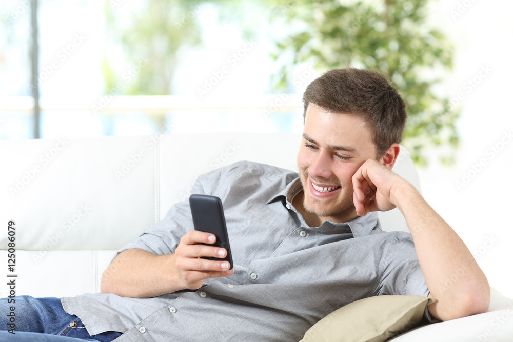 Man using a smartphone sitting on a couch Man using a smartphone sitting on a couch
