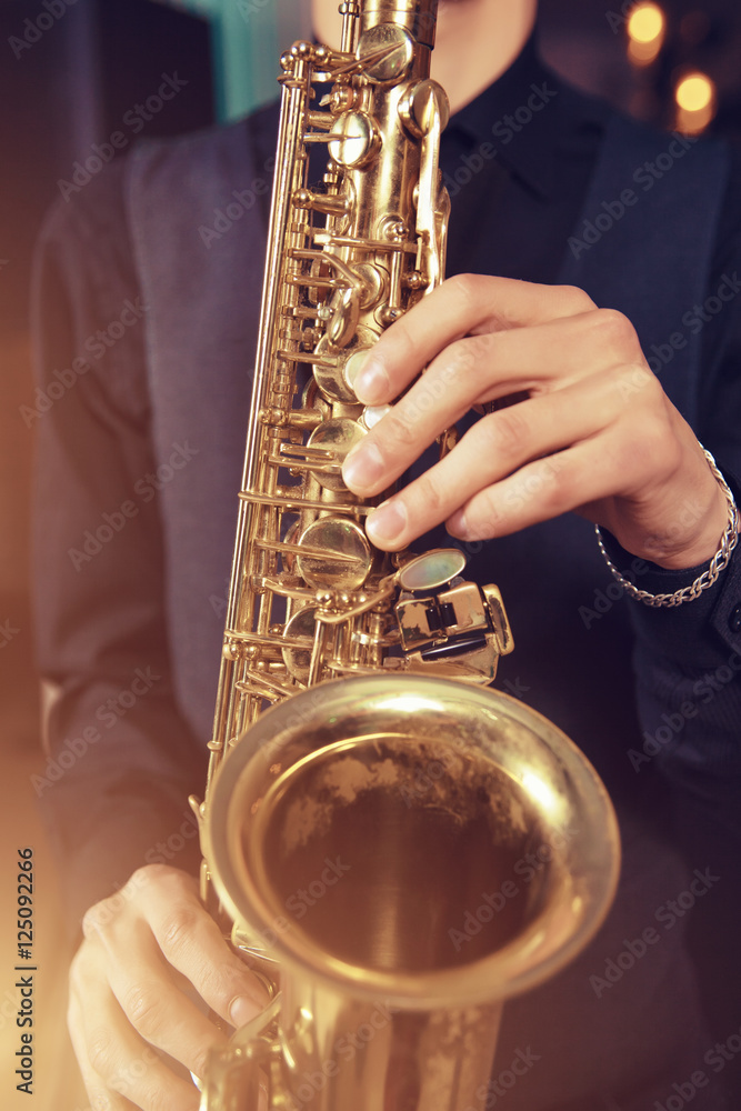 Obraz premium Musical instrument saxophone close-up. Hands on a musical instrument. Young guy playing jazz.