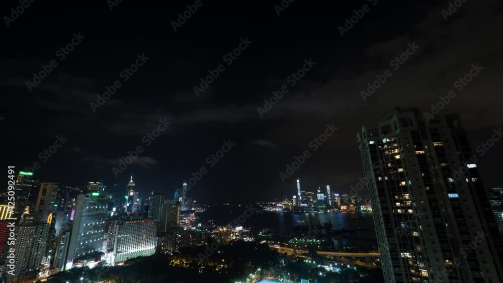 Timelapse shot of night life in Hong Kong. City panorama with illuminated buildings, Symphony of Lights, traffic in harbour and clouds sailing on dark sky Timelapse shot of night life in Hong Kong. City panorama with illuminated buildings, Symphony of Lights, traffic in harbour and clouds sailing on dark sky