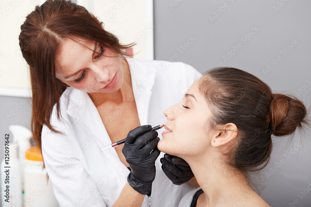 Cosmetologist applying permanent make up on lips Cosmetologist applying permanent make up on lips