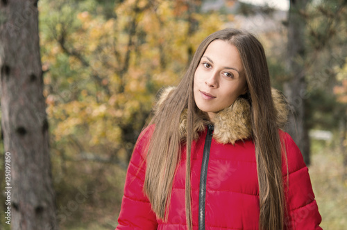 Young woman alone on a forest wearing red overcoat