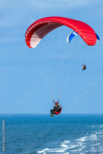 Lot paralotnią nad morzem w słoneczny dzień na tle błękitnego nieba 