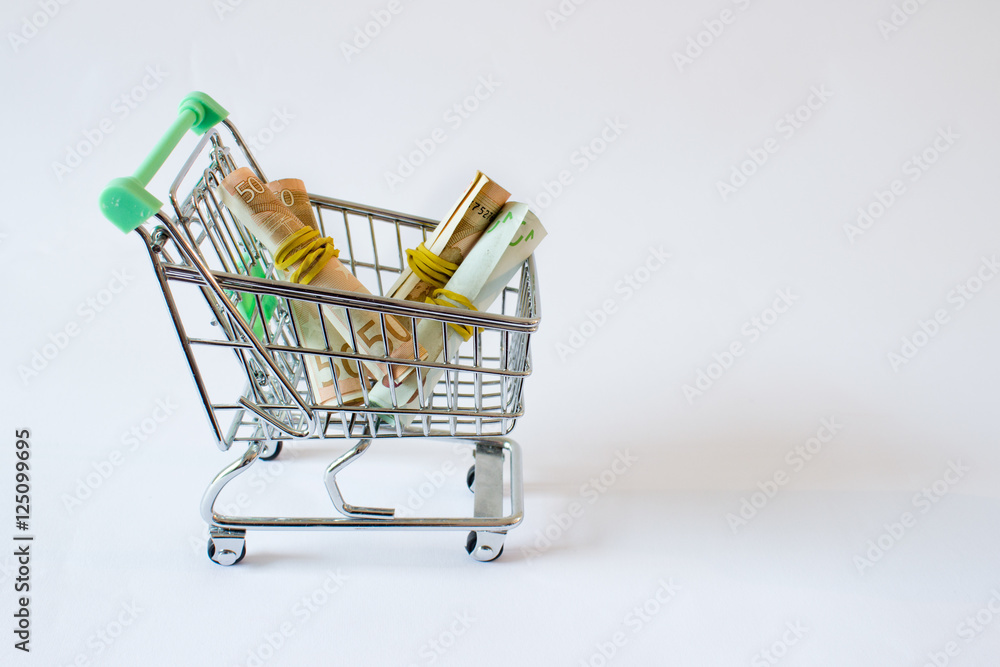 Conceptual studio shot of a bunch of euro banknotes filling a shopping cart on white background Conceptual studio shot of a bunch of euro banknotes filling a shopping cart on white background