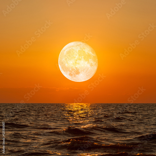 Full moon rising over empty ocean at night