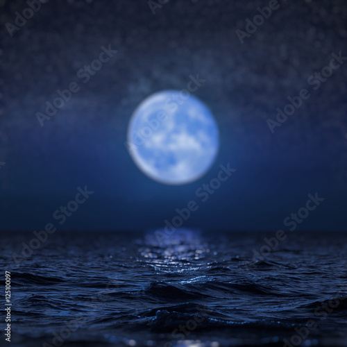 Full moon rising over empty ocean at night, blur background