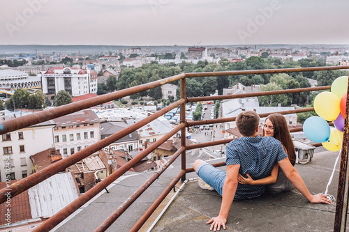 Young couple exploring an old town. Man pointing at some landmark. Man and woman with baloonsvisiting city and enjoying view. building city administration currently open view point for tourists. 