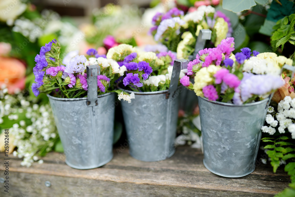 Three buckets of beautiful purple and white flowers prepared for wedding ceremony