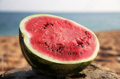 Photography Half of ripe juicy watermelon on stone at beach