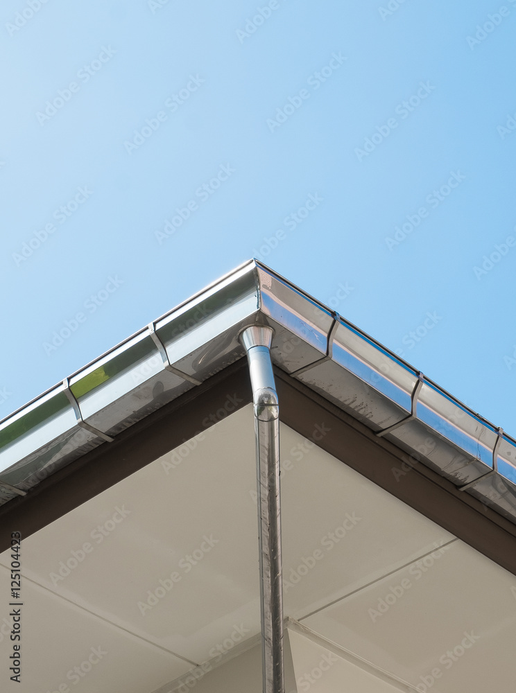 Rain gutter system on roof of House against Blue Sky Rain gutter system on roof of House against Blue Sky