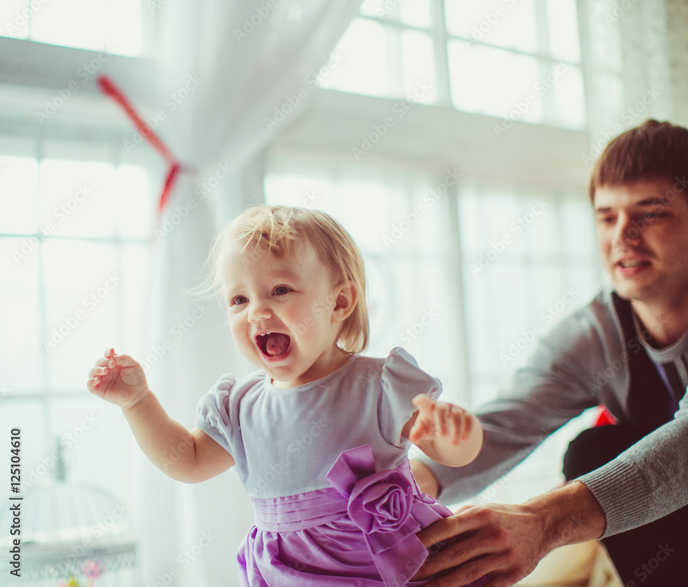 Blonde child laughs while running from her dad before a white wi