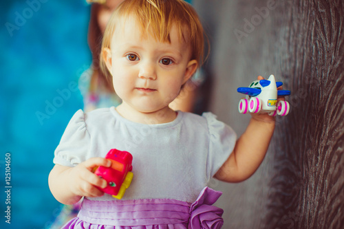 Little girl with deep hazel eyes holds in her tiny arms an airpl photo