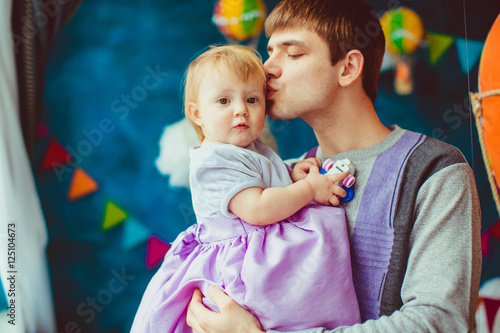 Dad kisses head of his little daughter while they stand before a