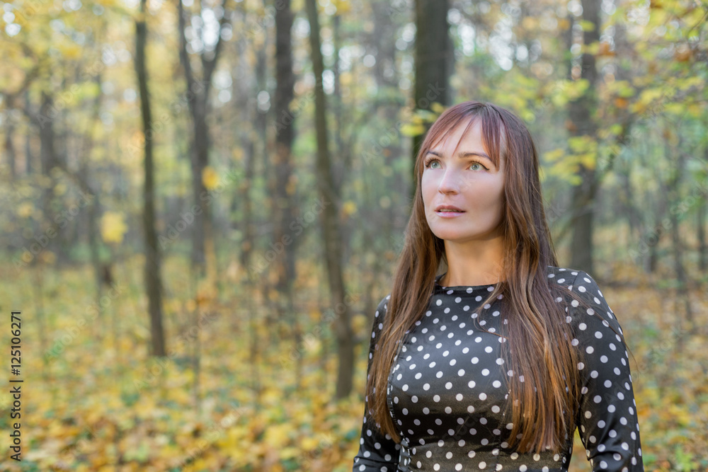 beautiful girl in autumn forest looking into the distance
