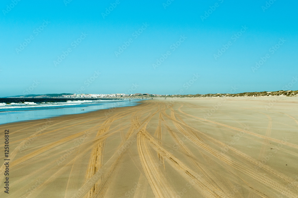 Orilla de playa con marcas de ruedas de coche