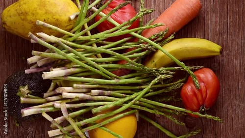 some fruits and vegetables being placed or dropped on a rustic wooden table