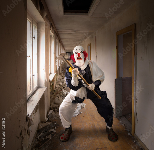 evil clown with a hammer standing in a broken corridor