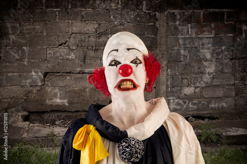 angry clown standing in front of a wall photo