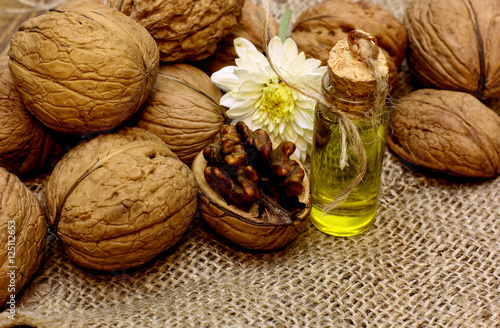 Walnut oil and nuts on coarse cloth sacking and flower