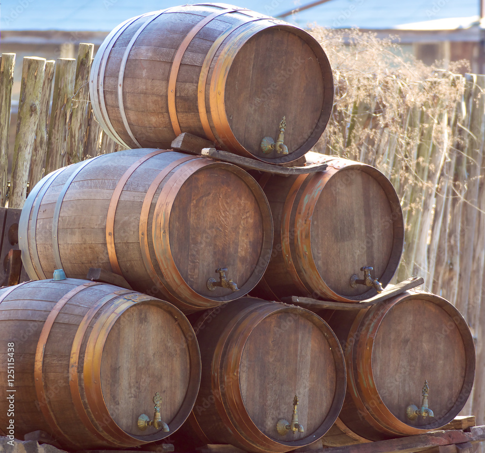 wooden wine barrels kegs stacked in pyramid outside cellar