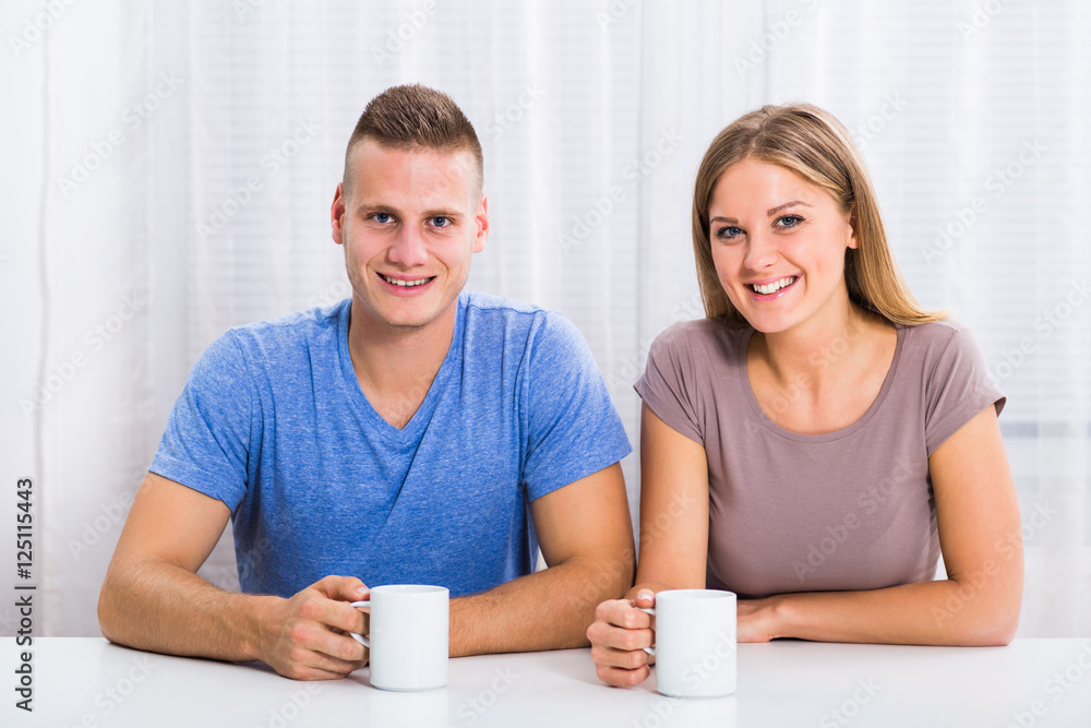 Young happy couple enjoys drinking coffee together.
Young happy couple enjoys drinking coffee together.