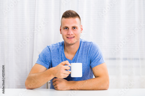 Young man enjoys drinking coffee at home.