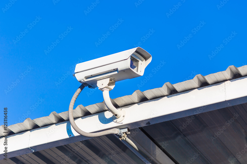 The close circuit camera on the roof with the blue sky background. The security system from the close-circuit camera.