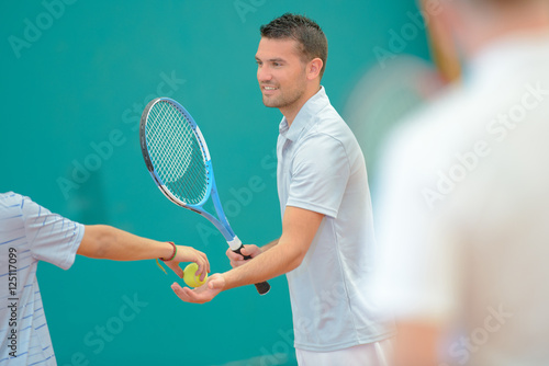 Male tennis player taking ball
